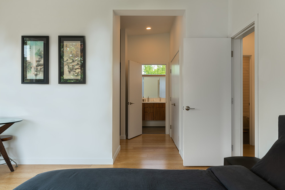 This is an example of a mid-sized contemporary master bedroom in Seattle with white walls, bamboo floors and brown floor.