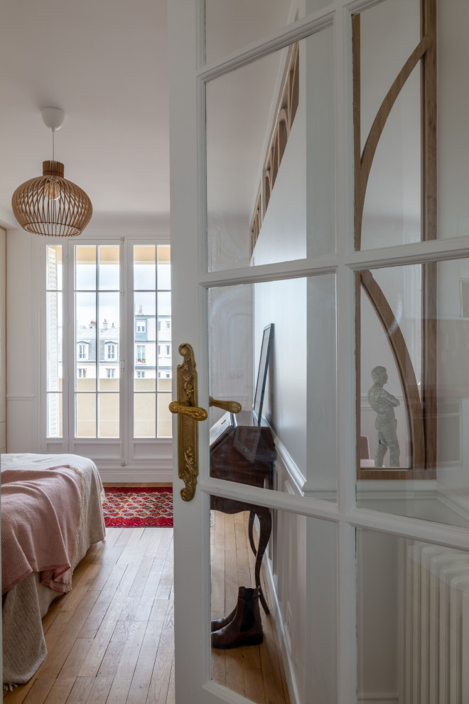 Design ideas for a mid-sized scandinavian master bedroom in Paris with white walls, light hardwood floors and decorative wall panelling.