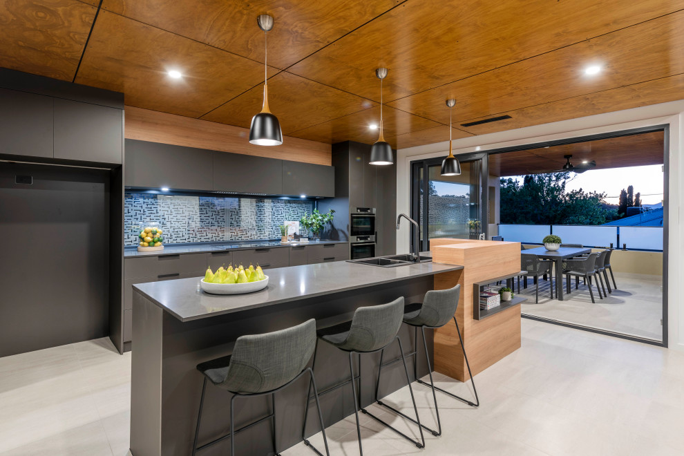 Design ideas for a large contemporary galley open plan kitchen in Canberra - Queanbeyan with flat-panel cabinets, black cabinets, glass sheet splashback, black appliances, light hardwood floors, with island, white floor and grey benchtop.