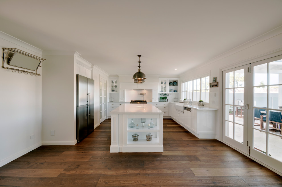 This is an example of a large traditional u-shaped kitchen in Brisbane with a farmhouse sink, shaker cabinets, white cabinets, quartz benchtops, white splashback, subway tile splashback, stainless steel appliances, medium hardwood floors and with island.