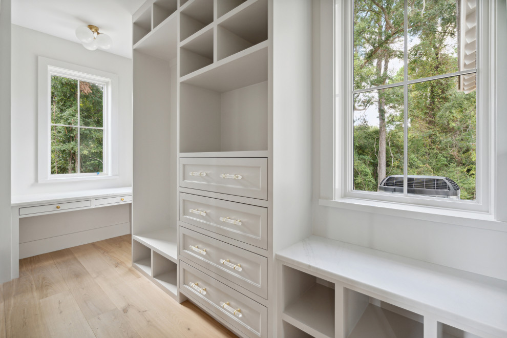 Foto di una cabina armadio minimalista con ante in stile shaker, ante beige e parquet chiaro