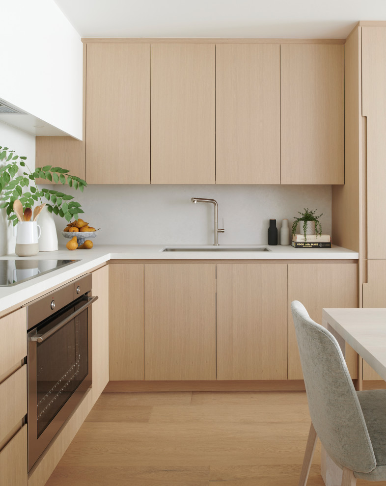 Inspiration for a small modern l-shaped light wood floor eat-in kitchen remodel in Toronto with an undermount sink, flat-panel cabinets, light wood cabinets, quartzite countertops, white backsplash, quartz backsplash, stainless steel appliances and white countertops