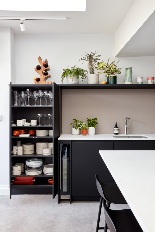 Inspiration for a mid-sized modern u-shaped eat-in kitchen in London with an integrated sink, flat-panel cabinets, black cabinets, quartz benchtops, pink splashback, glass sheet splashback, stainless steel appliances, with island and white benchtop.