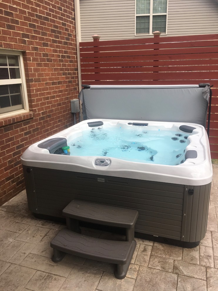 Example of a mid-sized transitional backyard stamped concrete and rectangular hot tub design