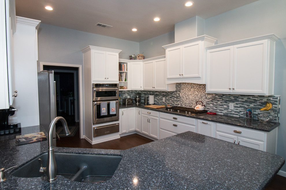 Example of a mid-sized transitional u-shaped porcelain tile and brown floor open concept kitchen design with an undermount sink, recessed-panel cabinets, white cabinets, quartz countertops, blue backsplash, mosaic tile backsplash, stainless steel appliances and blue countertops