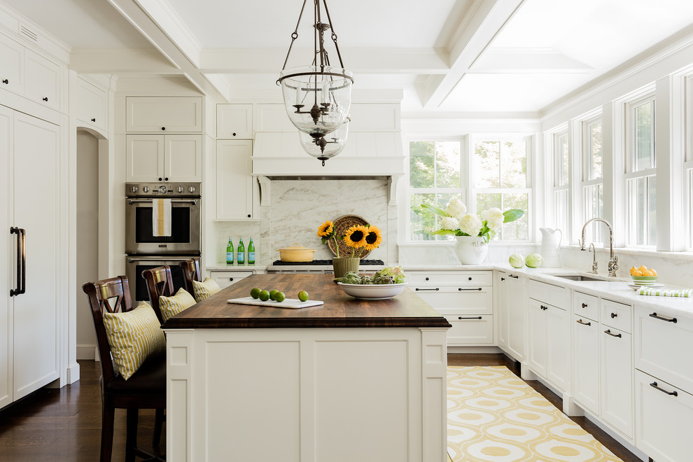 Inspiration for a traditional kitchen in Boston with an undermount sink, shaker cabinets, white cabinets, white splashback, marble splashback, panelled appliances, dark hardwood floors, with island, brown floor and wood benchtops.