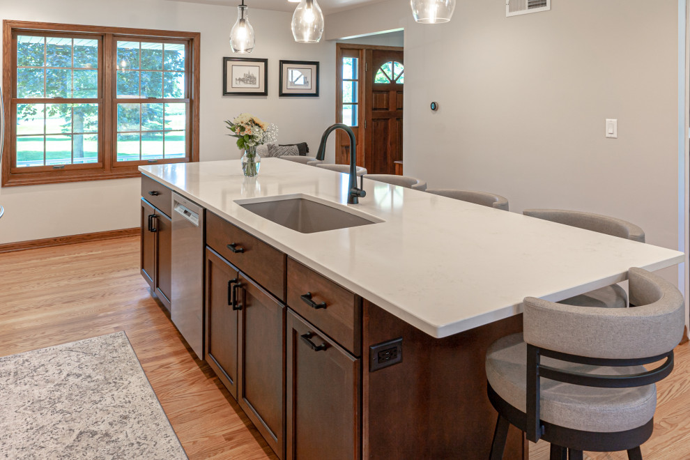 Inspiration for a large traditional l-shaped eat-in kitchen in Milwaukee with an undermount sink, recessed-panel cabinets, white cabinets, granite benchtops, grey splashback, mosaic tile splashback, stainless steel appliances, medium hardwood floors, with island, brown floor and multi-coloured benchtop.