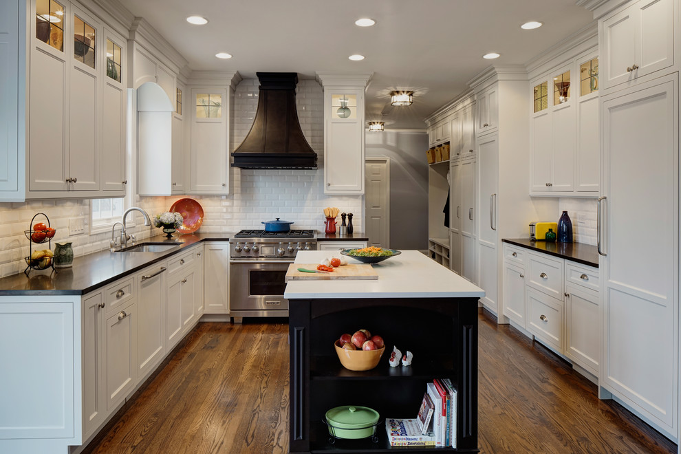 Photo of a mid-sized traditional u-shaped eat-in kitchen in Chicago with an undermount sink, beaded inset cabinets, white cabinets, granite benchtops, white splashback, subway tile splashback, panelled appliances, medium hardwood floors and with island.