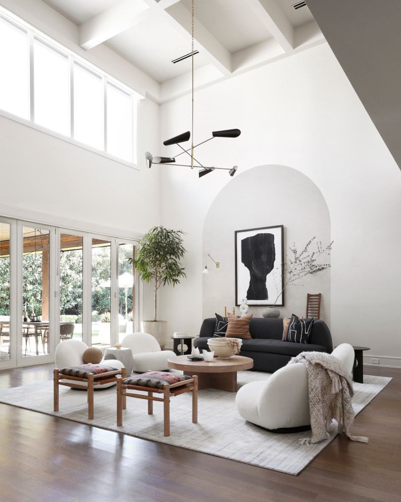 Пример оригинального дизайна: большая открытая гостиная комната в белых тонах с отделкой деревом в современном стиле с белыми стенами, скрытым телевизором, паркетным полом среднего тона и сводчатым потолком