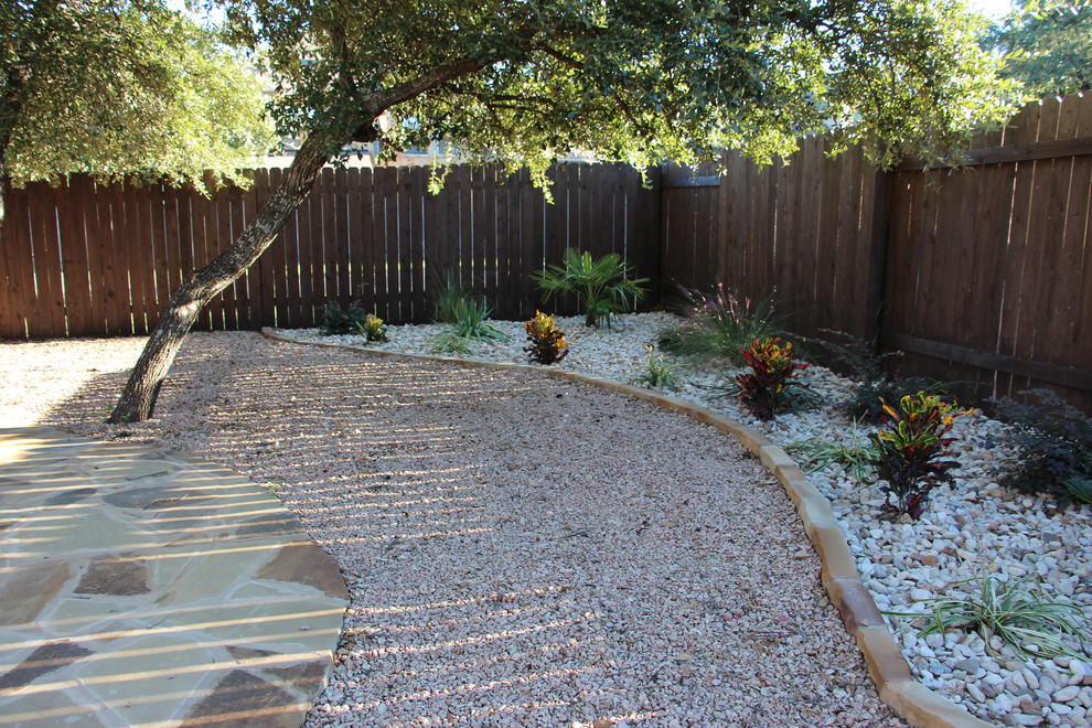This is an example of a mid-sized traditional backyard full sun xeriscape for summer in Austin with natural stone pavers.