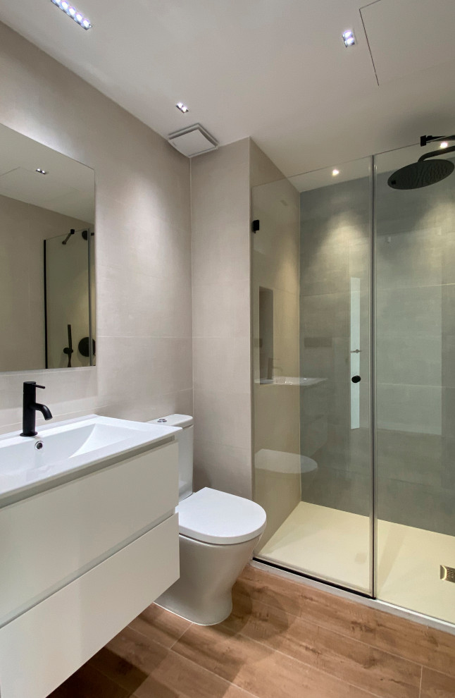 Mid-sized contemporary master bathroom in Barcelona with white cabinets, a curbless shower, a one-piece toilet, beige tile, beige walls, medium hardwood floors, an integrated sink, a sliding shower screen, white benchtops, an enclosed toilet, a single vanity and a built-in vanity.