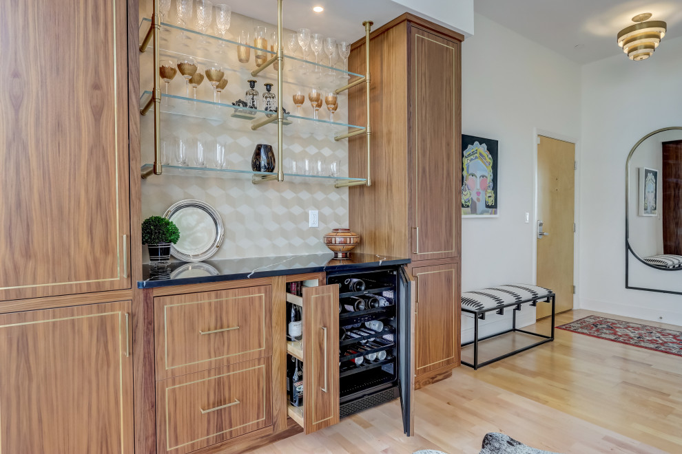 Inspiration for a small contemporary single-wall light wood floor and brown floor dry bar remodel in Milwaukee with no sink, floating shelves, medium tone wood cabinets, marble countertops, beige backsplash and black countertops