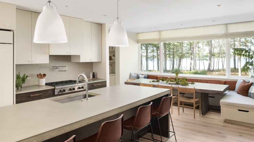 Beach style galley eat-in kitchen in Portland Maine with an undermount sink, flat-panel cabinets, dark wood cabinets, grey splashback, stainless steel appliances, light hardwood floors, with island, beige floor and white benchtop.