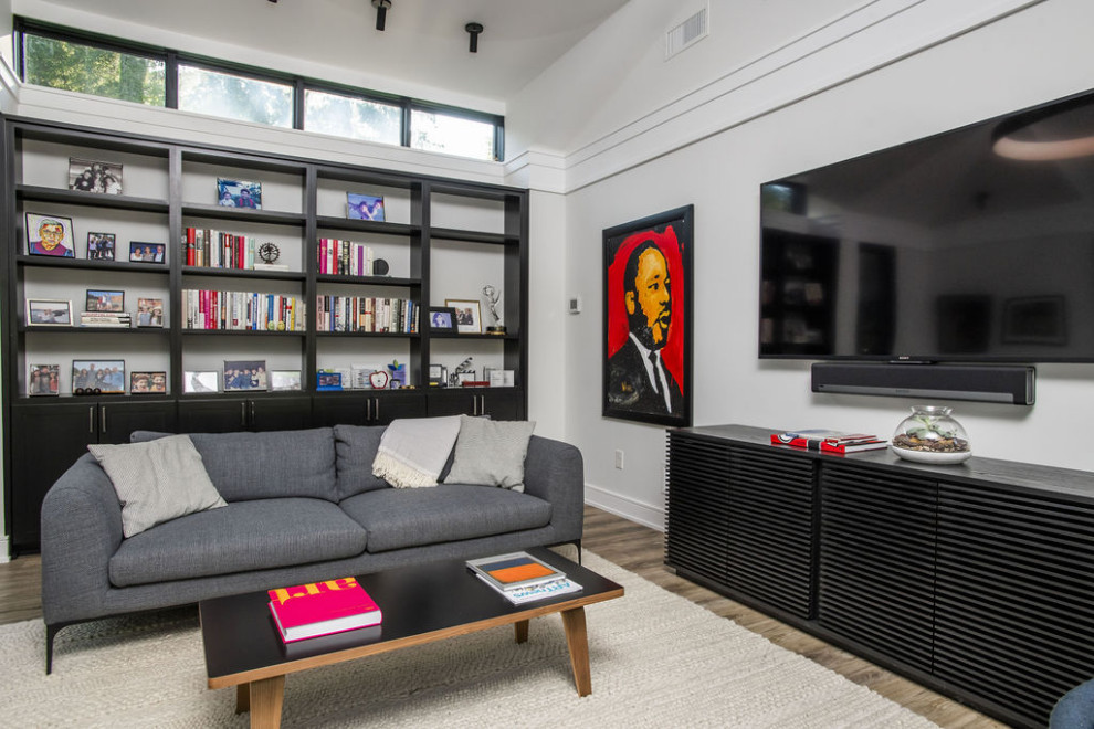Modern enclosed living room in Baltimore with a library, white walls, light hardwood floors, a wall-mounted tv, multi-coloured floor and vaulted.