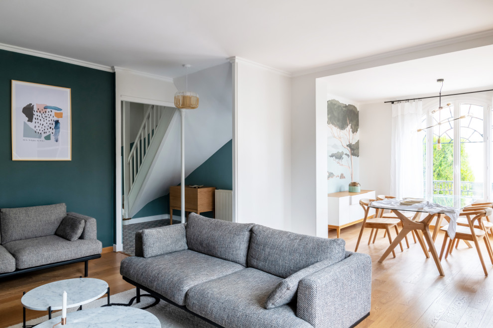 Großes, Offenes Modernes Wohnzimmer mit grüner Wandfarbe, hellem Holzboden, Kamin, Kaminumrandung aus Stein, TV-Wand, braunem Boden und vertäfelten Wänden in Paris