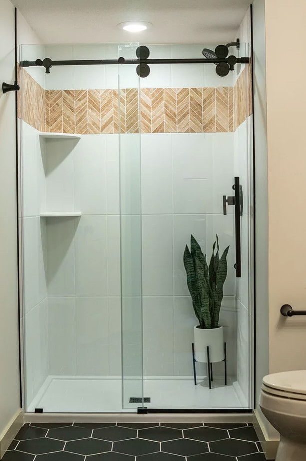 Пример оригинального дизайна: ванная комната, совмещенная с туалетом среднего размера в скандинавском стиле с плоскими фасадами, светлыми деревянными фасадами, душем в нише, белой плиткой, керамической плиткой, белыми стенами, полом из керамической плитки, душевой кабиной, монолитной раковиной, столешницей из искусственного камня, черным полом, душем с раздвижными дверями, белой столешницей, тумбой под одну раковину и напольной тумбой