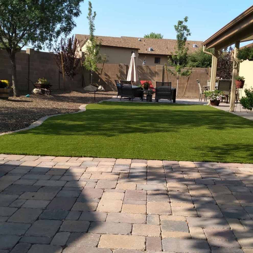 Großer Moderner Garten hinter dem Haus mit Rasenkanten, direkter Sonneneinstrahlung und Pflastersteinen in Phoenix