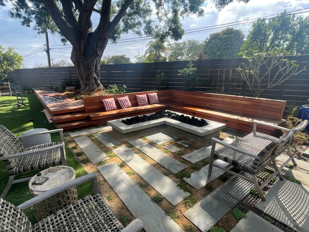 Small midcentury backyard patio in Los Angeles with a fire feature and natural stone pavers.