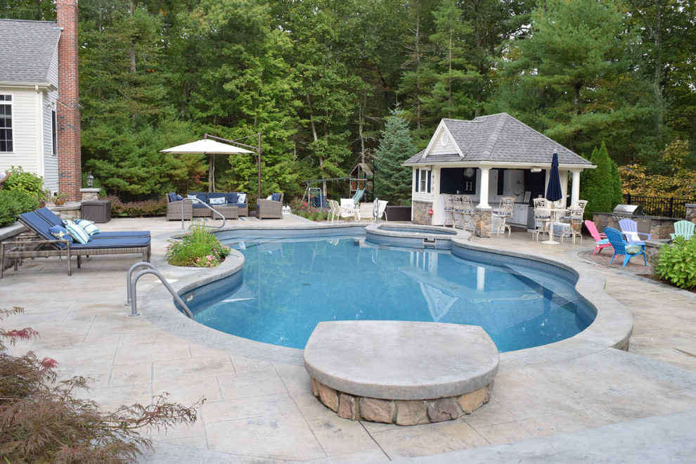 Inspiration for a mid-sized traditional backyard kidney-shaped lap pool in Providence with a pool house and stamped concrete.