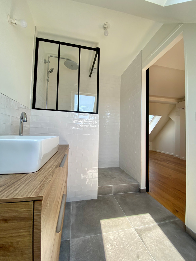 Photo of a mid-sized traditional master bathroom in Paris with recessed-panel cabinets, light wood cabinets, a double shower, white tile, matchstick tile, white walls, cement tiles, a trough sink, solid surface benchtops, grey floor, an open shower, beige benchtops, a single vanity and a floating vanity.