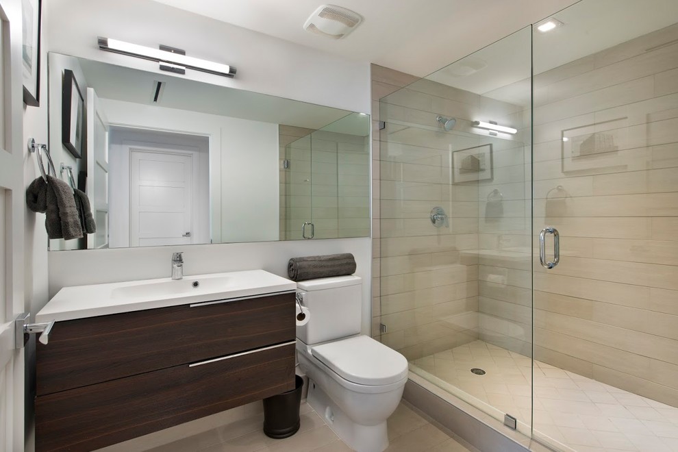 Photo of a mid-sized contemporary 3/4 bathroom in Miami with flat-panel cabinets, dark wood cabinets, an alcove shower, a two-piece toilet, beige tile, white walls, an integrated sink and a sliding shower screen.