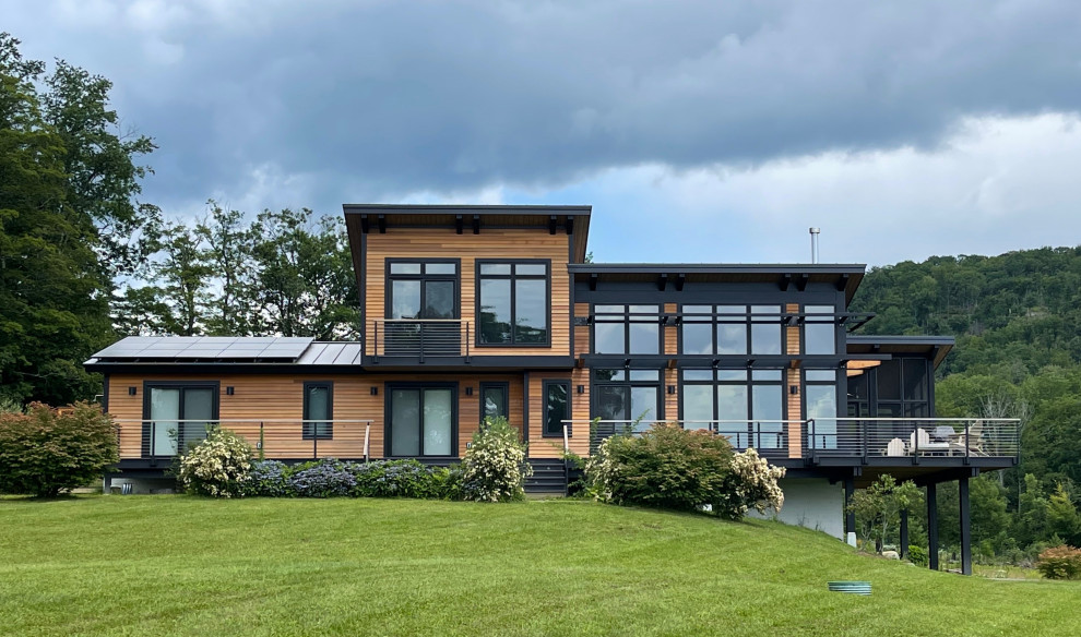 Ispirazione per la facciata di una casa marrone contemporanea a due piani di medie dimensioni con rivestimento in legno, copertura in metallo o lamiera, tetto nero e pannelli sovrapposti