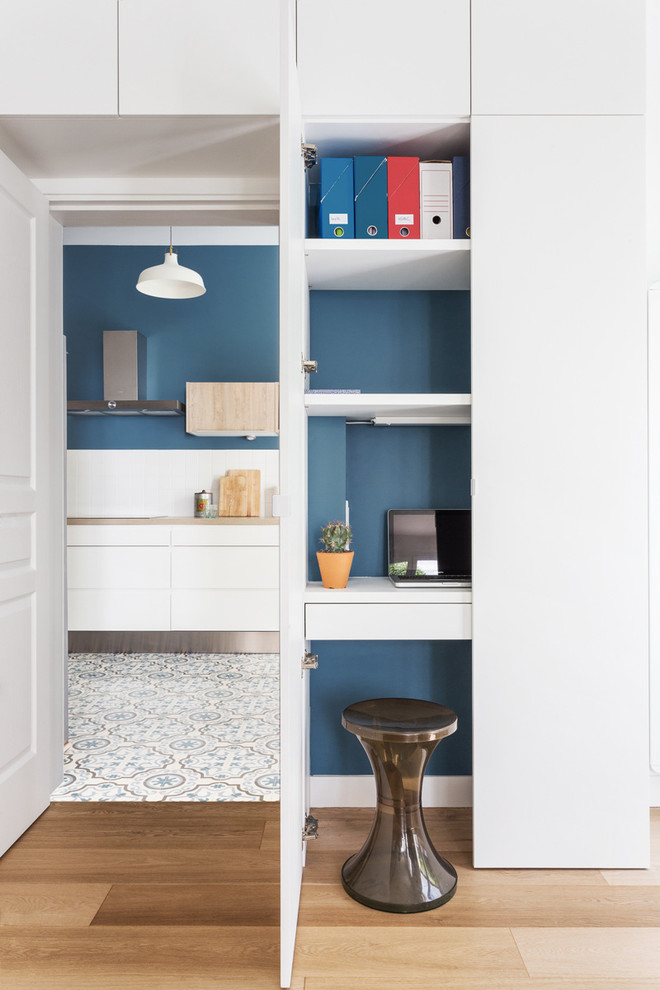 Inspiration för små skandinaviska hemmabibliotek, med blå väggar, mellanmörkt trägolv och ett inbyggt skrivbord