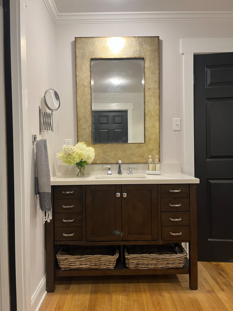 Inspiration for a large transitional light wood floor, brown floor and double-sink freestanding bathtub remodel with raised-panel cabinets, dark wood cabinets, a two-piece toilet, white walls, an undermount sink, quartz countertops, white countertops and a built-in vanity