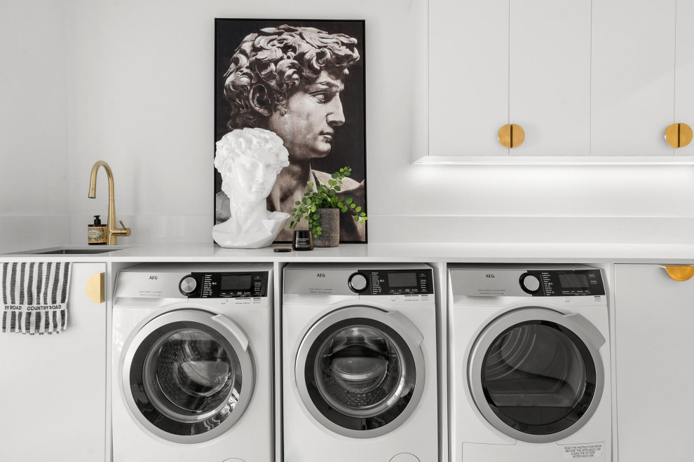 Design ideas for a large contemporary galley dedicated laundry room in Sydney with an undermount sink, flat-panel cabinets, quartz benchtops, white splashback, engineered quartz splashback, white walls, porcelain floors, a side-by-side washer and dryer, grey floor and white benchtop.