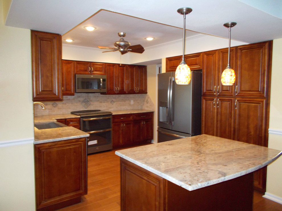 This is an example of a traditional kitchen in Tampa with beaded inset cabinets, medium wood cabinets, beige splashback, stainless steel appliances, medium hardwood floors and with island.