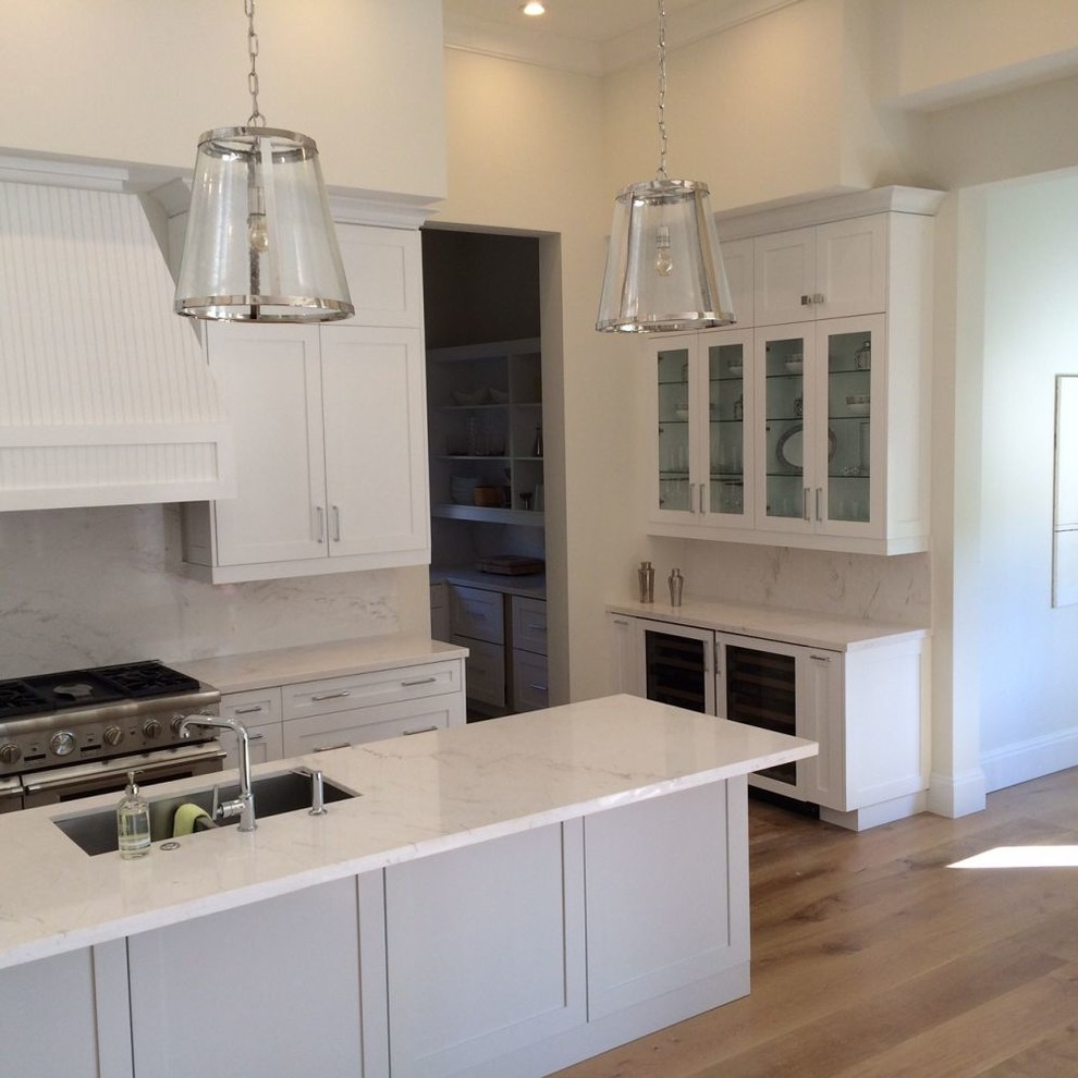 Example of a large transitional u-shaped light wood floor and beige floor eat-in kitchen design in Miami with an undermount sink, recessed-panel cabinets, white cabinets, marble countertops, white backsplash, stone slab backsplash, paneled appliances, an island and white countertops