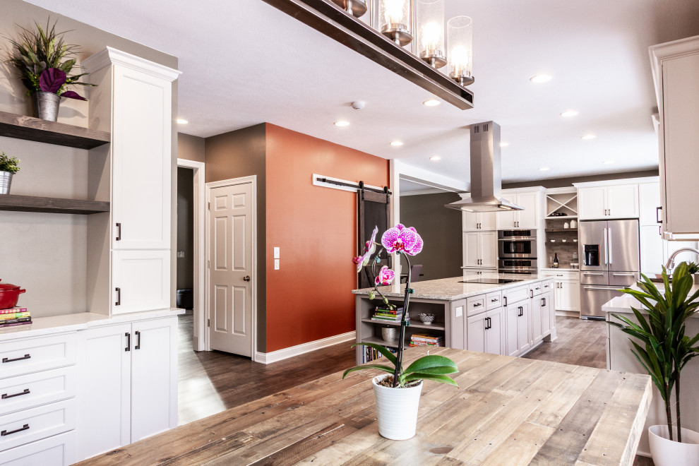 Large transitional l-shaped eat-in kitchen in Indianapolis with a farmhouse sink, flat-panel cabinets, white cabinets, quartz benchtops, subway tile splashback, stainless steel appliances and with island.