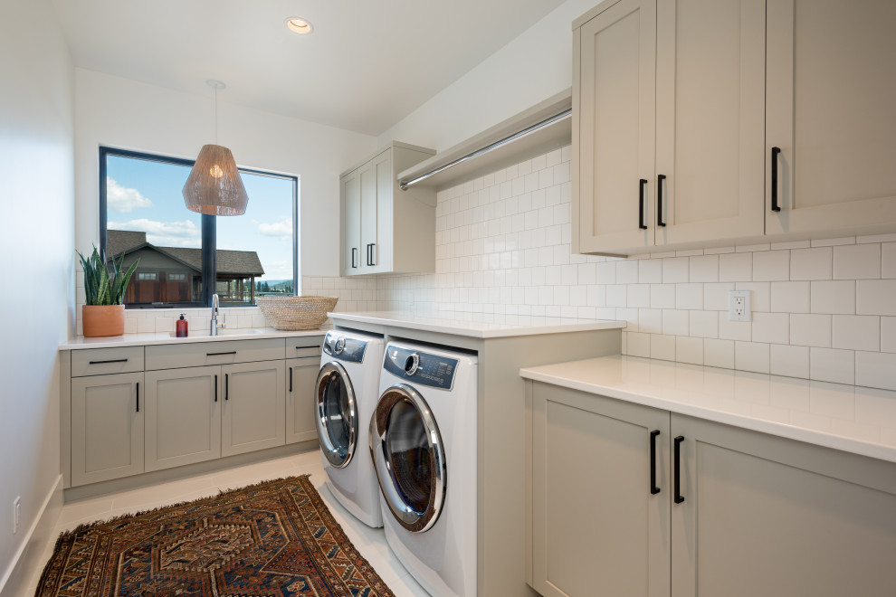 Beach style l-shaped dedicated laundry room in Seattle with an undermount sink, shaker cabinets, quartz benchtops, white splashback, subway tile splashback, white walls, a side-by-side washer and dryer and white benchtop.