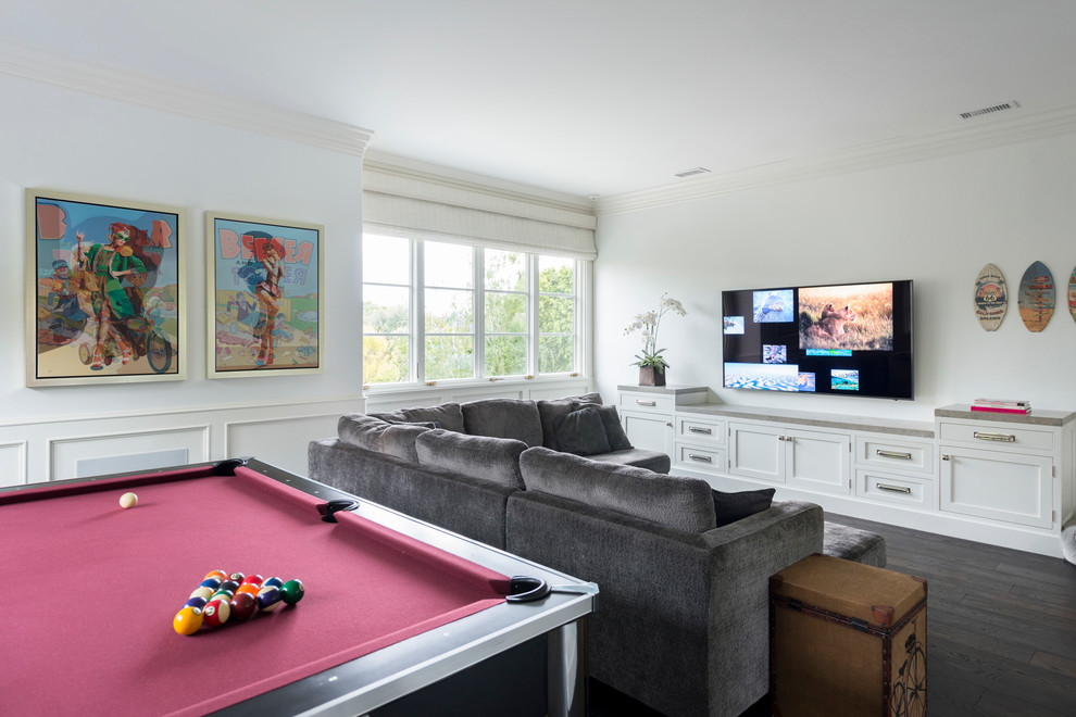 This is an example of a large transitional family room in Los Angeles with white walls, dark hardwood floors, brown floor, a game room and a built-in media wall.