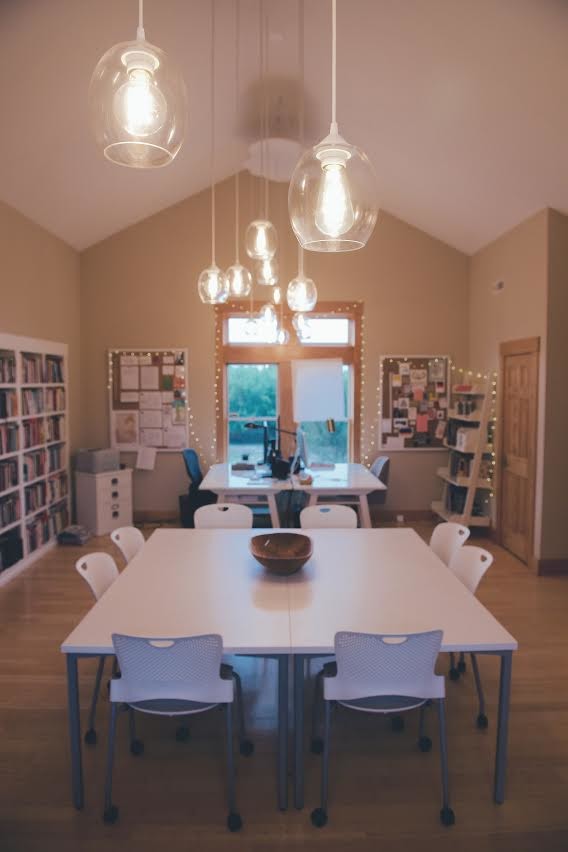 Photo of a large contemporary home office in Kansas City with a library, beige walls, medium hardwood floors, no fireplace, a freestanding desk and brown floor.
