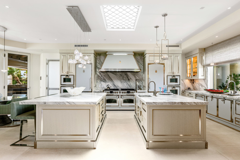 Immagine di un'ampia cucina contemporanea con lavello integrato, ante in acciaio inossidabile, top in marmo, paraspruzzi bianco, paraspruzzi in marmo, elettrodomestici bianchi, 2 o più isole, pavimento beige e top bianco