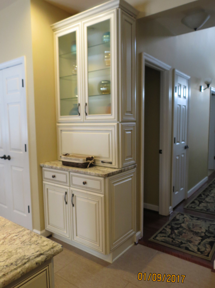 Inspiration for a mid-sized transitional l-shaped ceramic tile eat-in kitchen remodel with an undermount sink, raised-panel cabinets, distressed cabinets, granite countertops, white backsplash, porcelain backsplash, stainless steel appliances and an island
