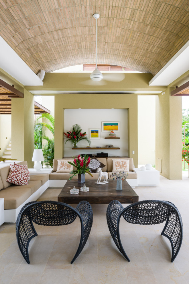 Foto di un grande soggiorno tropicale con pareti verdi, pavimento in pietra calcarea, soffitto a volta e pareti in mattoni