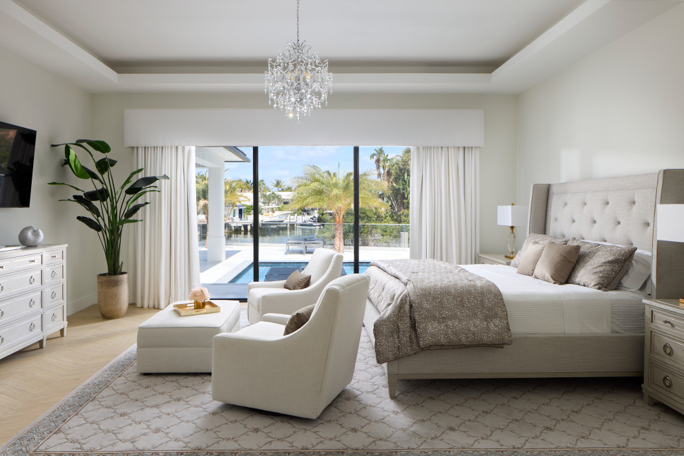Example of a beach style light wood floor, beige floor and tray ceiling bedroom design in Miami with white walls