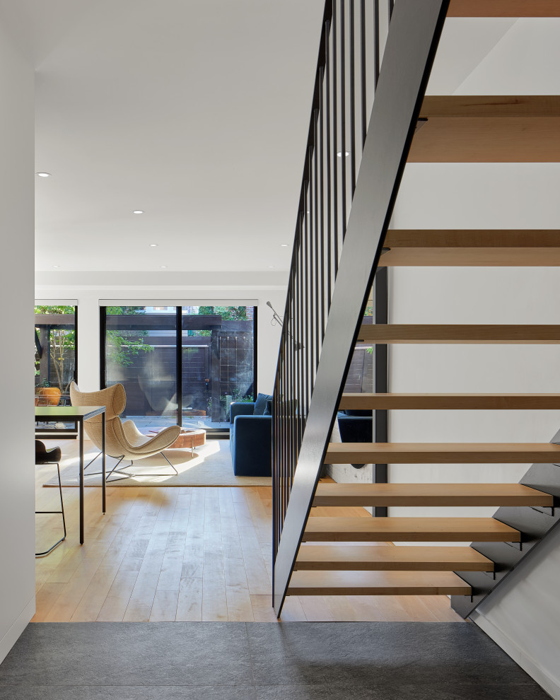 Inspiration for a mid-sized modern wood floating staircase in Montreal with open risers, metal railing and brick walls.