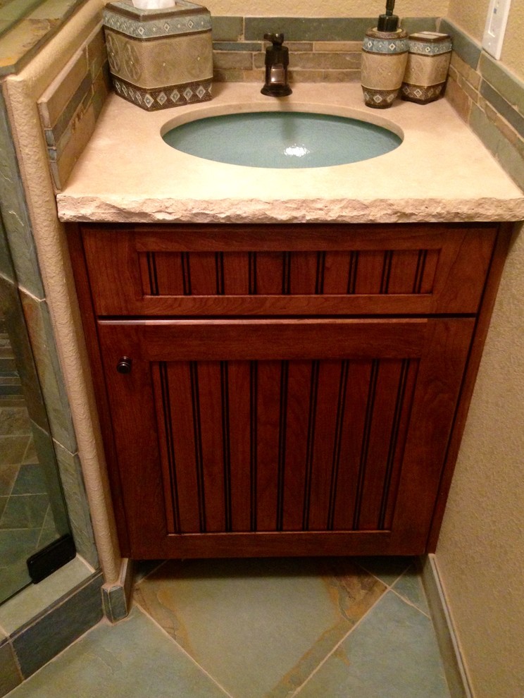 Small country 3/4 bathroom in Phoenix with an undermount sink, beaded inset cabinets, medium wood cabinets, a corner shower, a two-piece toilet, stone tile, beige walls and slate floors.