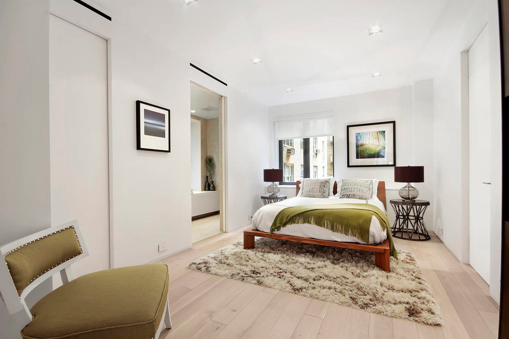 This is an example of a scandinavian bedroom in New York with white walls and light hardwood floors.