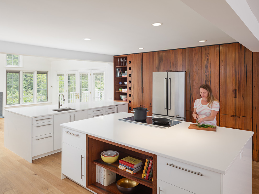 Inspiration for a large modern u-shaped eat-in kitchen in Philadelphia with flat-panel cabinets, dark wood cabinets, stainless steel appliances, light hardwood floors, with island, an undermount sink, quartz benchtops, beige floor and white benchtop.