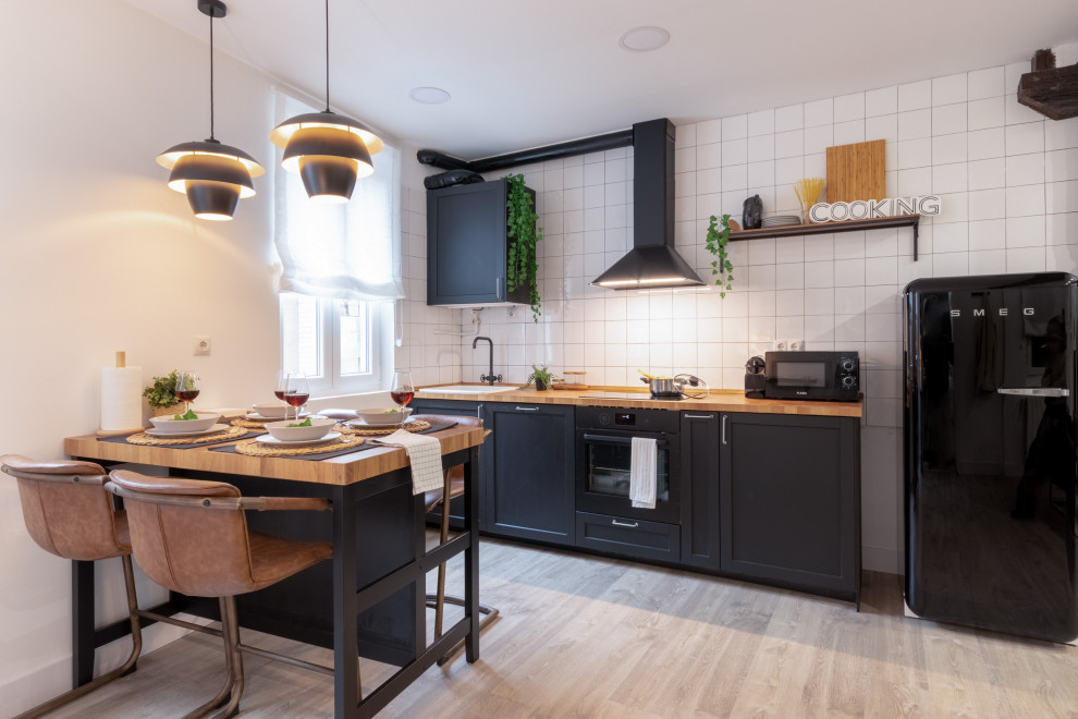 Inspiration for a small contemporary single-wall eat-in kitchen in Other with a drop-in sink, shaker cabinets, black cabinets, wood benchtops, white splashback, porcelain splashback, black appliances, grey floor and beige benchtop.