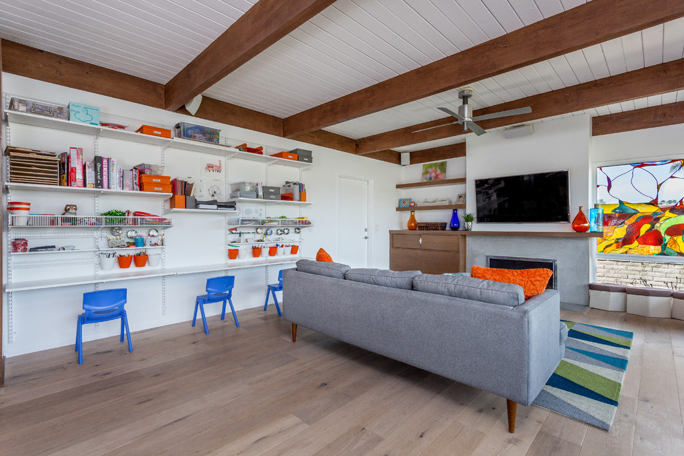 Mid-sized midcentury open concept family room in Orange County with white walls, light hardwood floors, a standard fireplace, a concrete fireplace surround and a wall-mounted tv.