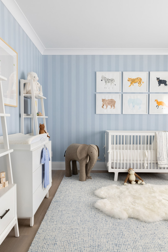 Example of a large classic boy light wood floor and brown floor nursery design in New York with blue walls