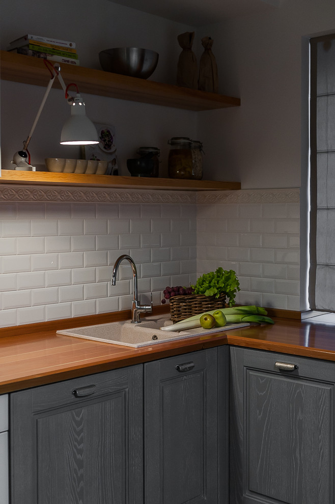 Design ideas for a small scandinavian l-shaped eat-in kitchen in Other with an undermount sink, raised-panel cabinets, grey cabinets, wood benchtops, white splashback, subway tile splashback, white appliances, ceramic floors, grey floor and brown benchtop.