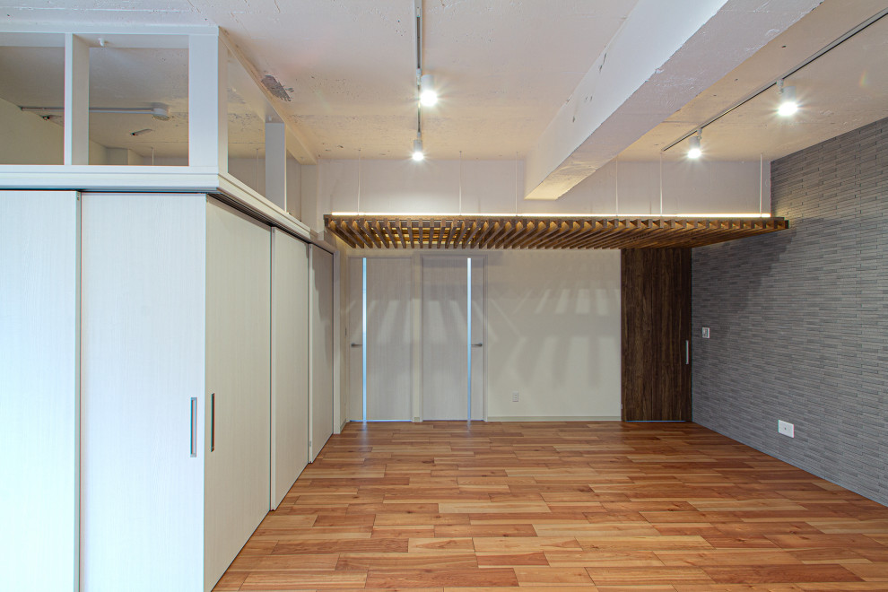 Esempio di un soggiorno industriale di medie dimensioni e aperto con pareti grigie, parquet scuro, pavimento marrone e pareti in mattoni