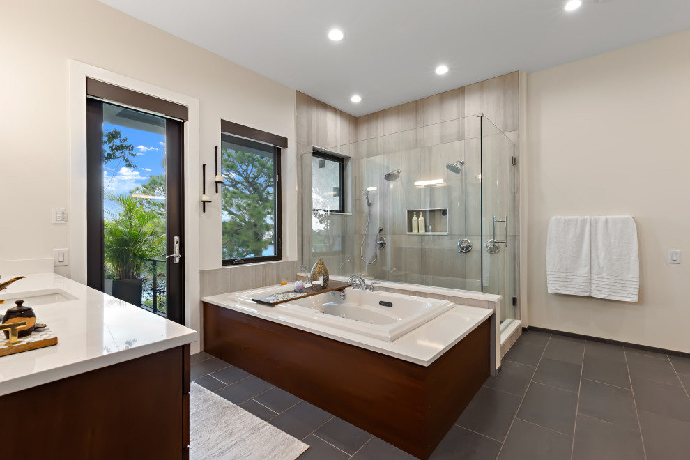 This is an example of a mid-sized contemporary master bathroom in Tampa with flat-panel cabinets, dark wood cabinets, a hot tub, a corner shower, gray tile, stone tile, beige walls, porcelain floors, an undermount sink, engineered quartz benchtops, grey floor, a hinged shower door, white benchtops, a single vanity and a built-in vanity.
