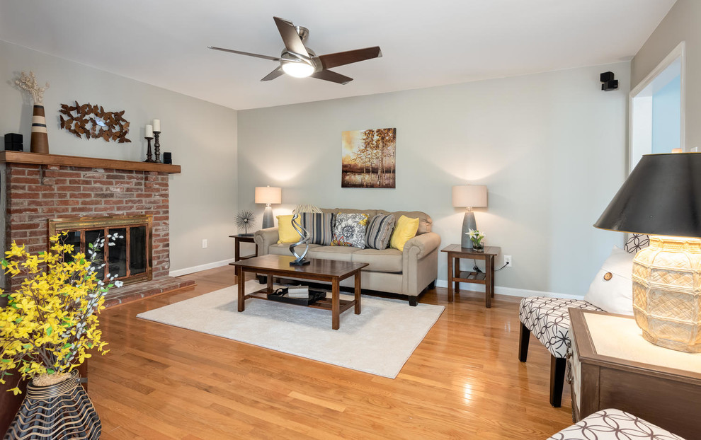 Mid-sized traditional enclosed family room in Philadelphia with grey walls, medium hardwood floors, a standard fireplace, a brick fireplace surround and brown floor.